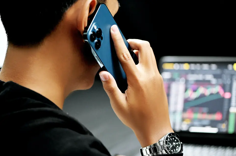 man in black long sleeve shirt holding blue smartphone looking at charts